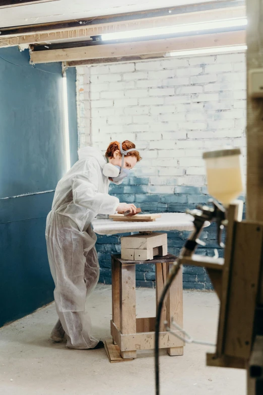 a woman in a lab coat working on a piece of wood, an airbrush painting, trending on unsplash, arbeitsrat für kunst, masked person in corner, flour dust spray, full length shot, thumbnail