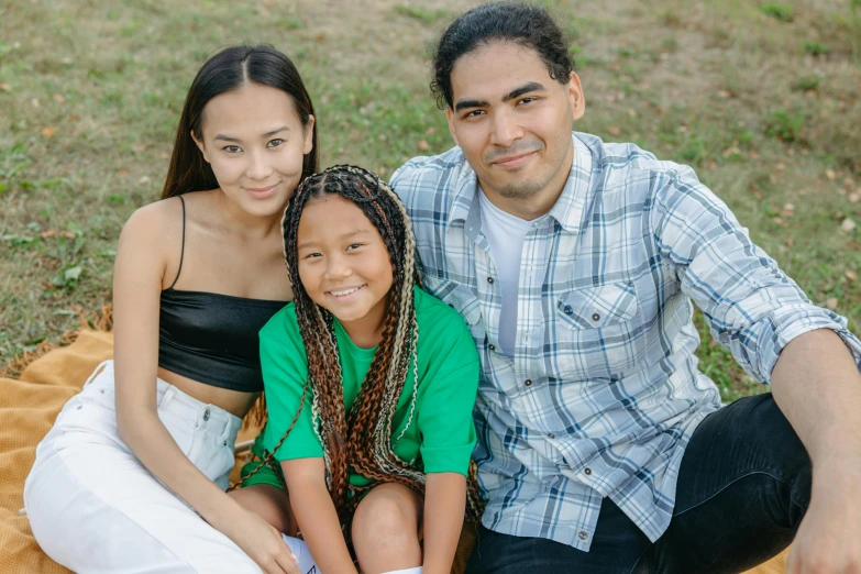 a man and woman sitting next to each other on a blanket, with a kid, andrew thomas huang, light-brown skin, ethnicity : japanese