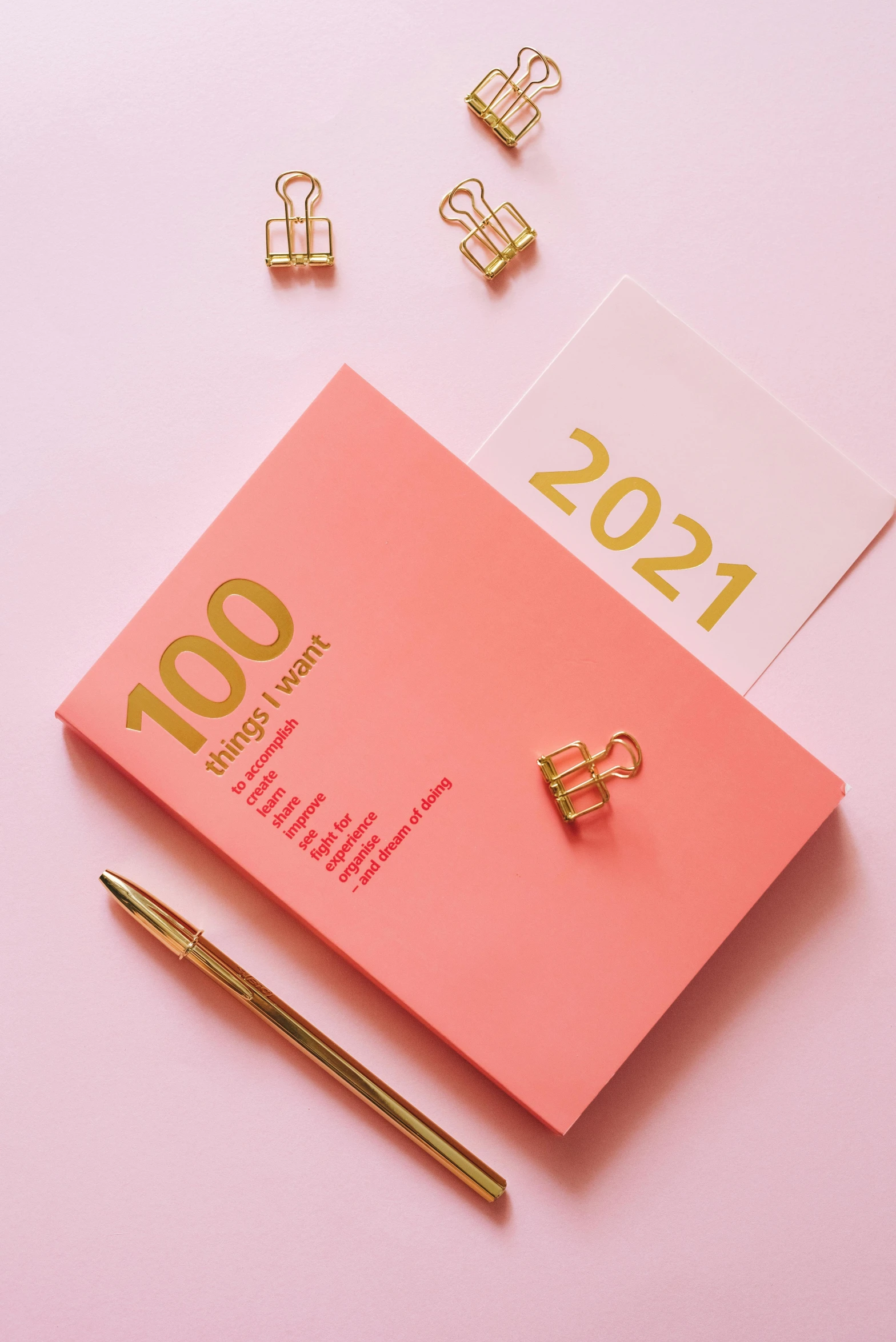 a pink notebook sitting on top of a pink surface, by Julia Pishtar, trending on unsplash, sign that says 1 0 0, gold accessories, unkown year, post graduate