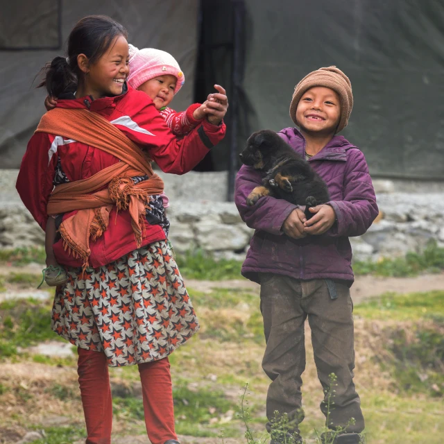 a couple of kids standing next to each other, by Jan Tengnagel, pexels contest winner, young himalayan woman, she is holding a cat in her arms, local people chasing to attack, slide show