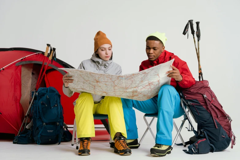 two people sitting in chairs looking at a map, by Alice Mason, trending on pexels, red sport clothing, wearing adventure gear, chartreuse and orange and cyan, model pose