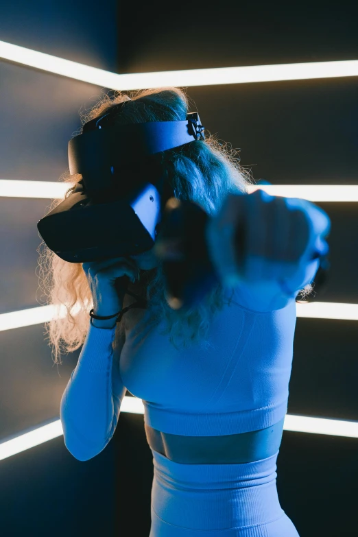 a woman standing in front of a wall with neon lights, a hologram, trending on pexels, interactive art, wrestlers wearing vr headsets, punching, sleek oled blue visor for eyes, a high angle shot