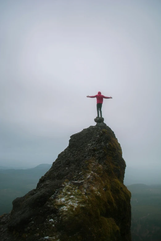 a person standing on top of a large rock, on a cloudy day, with arms up, 1km tall, skye meaker