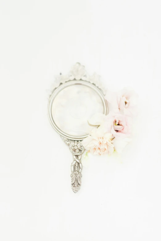 a mirror sitting on top of a table next to a flower, by Lynn Pauley, on white background, dreamy and detailed, silver，ivory, soft blush