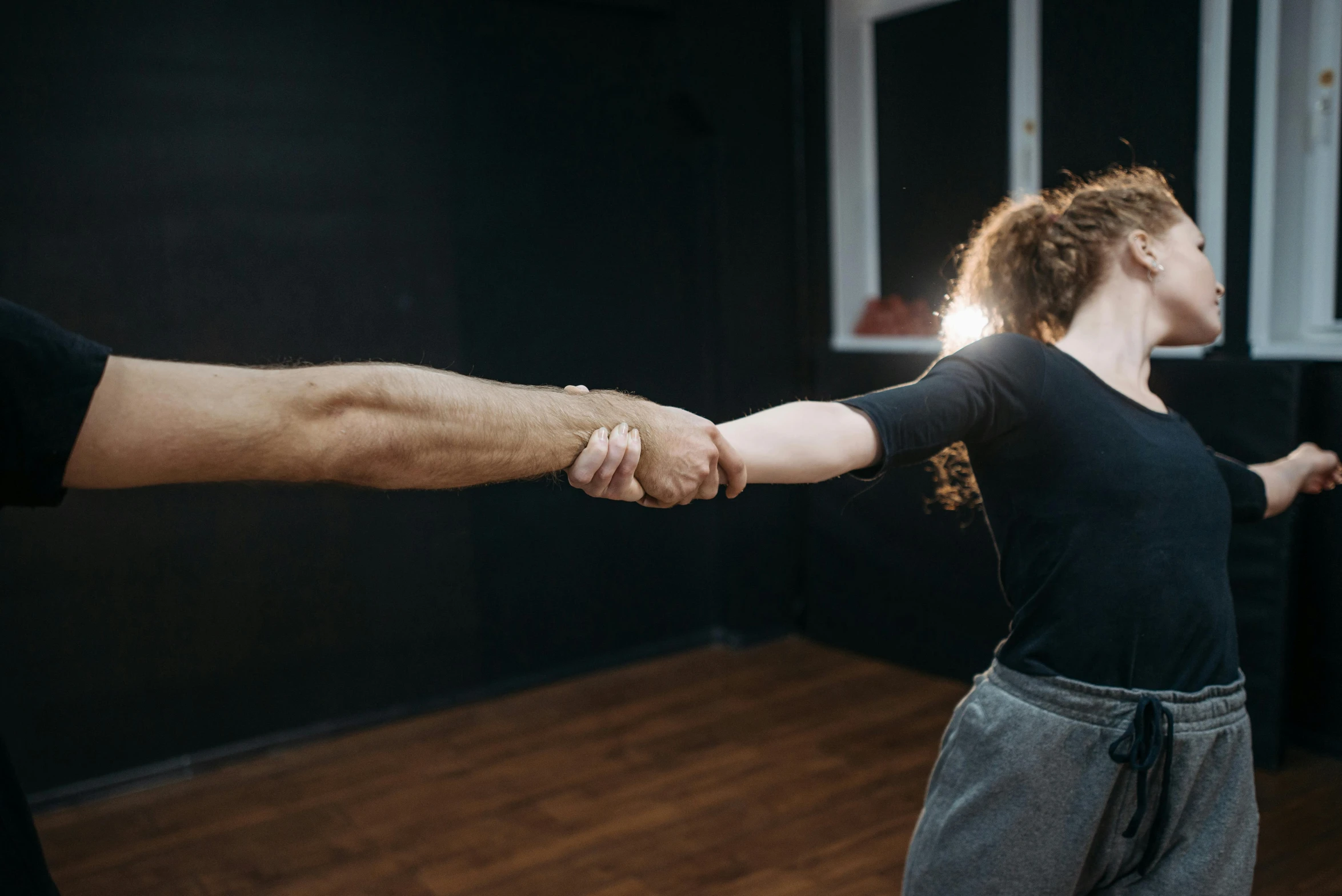 a man and a woman holding hands in a dance studio, by Emma Andijewska, unsplash, fist fight, background image, low quality photo, lachlan bailey