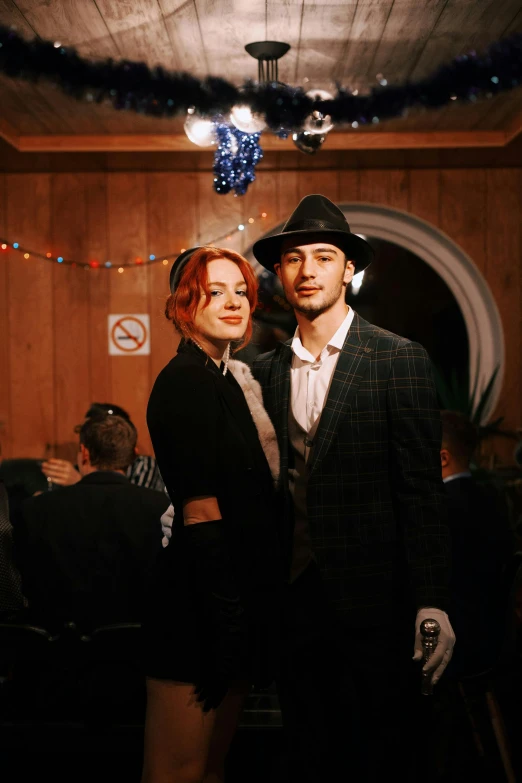 a man and a woman standing next to each other, reddit, antipodeans, at a birthday party, a suited man in a hat, dasha taran, with red hair