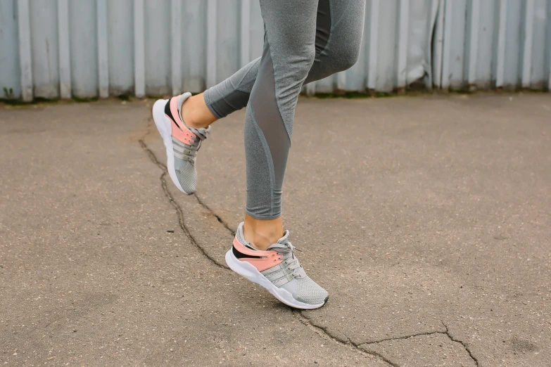 a close up of a person on a skateboard, running shoes, pink and grey muted colors, leggings, vsx