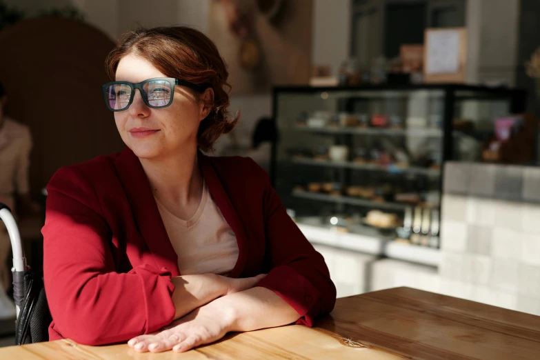 a woman in glasses sitting at a table, pexels contest winner, bakery, lachlan bailey, avatar image, uncropped