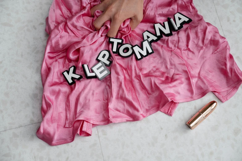 a woman in a pink dress laying on the floor, an album cover, featured on instagram, antipodeans, short puffy pants made of silk, typographic, close-up product photo, kodachromatic