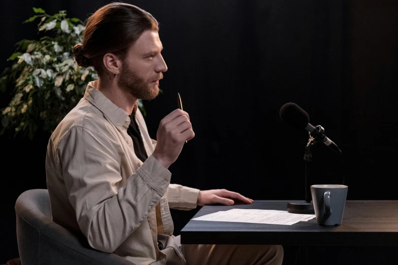 a man sitting at a desk in front of a microphone, trending on reddit, fantastic realism, holding a magic needle, press shot, ready to eat, royal commission