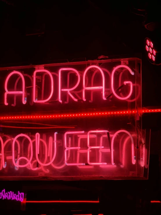 a neon sign on the side of a building, drag queen, addams, adar darnov, halloween night