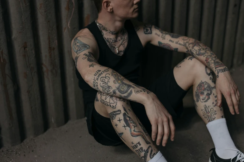 a man with tattoos sitting on the ground, a tattoo, inspired by Seb McKinnon, trending on pexels, non binary model, detailed arms, male character, federation clothing