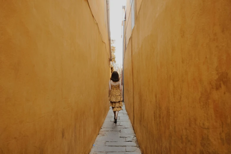 a woman walking down a narrow alley way, unsplash contest winner, yellow ocre tint dominant, minimalist photo, jenny seville, girl