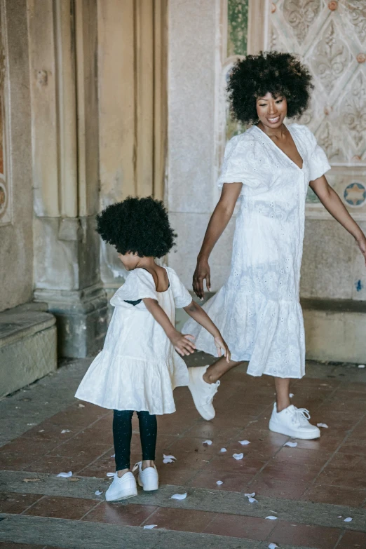 a woman in a white dress and a little girl in a white dress, pexels contest winner, arabesque, with afro, wearing white sneakers, promotional image, in barcelona