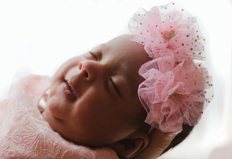 a close up of a baby wearing a pink dress, wearing a flower headpiece, brown skinned, smiling in heaven, bows