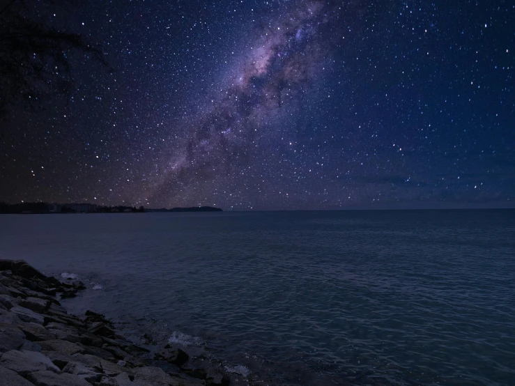 the milky shines brightly in the sky above the ocean, a portrait, by Peter Churcher, night sky photography, grey