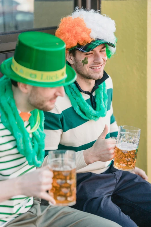 a couple of men sitting next to each other, by Adam Marczyński, shutterstock, wearing green tophat, beer glasses, irish, striped