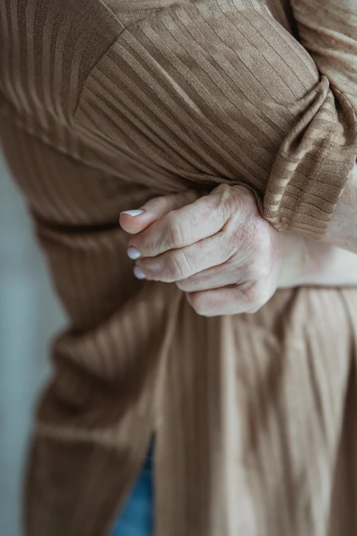 a close up of a person wearing a brown shirt, by Adam Marczyński, pexels, her hand is on her waist, recovering from pain, older woman, puff sleeves