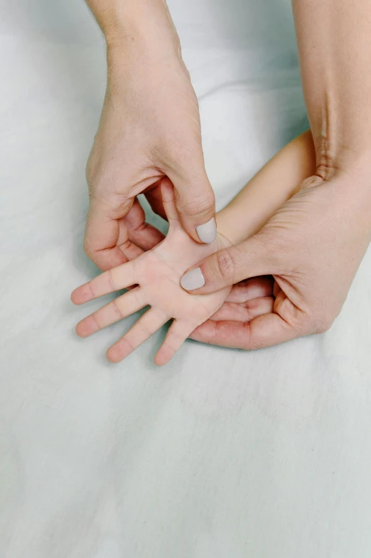 a close up of a person's hands on a bed, rubbery, children's, silicone skin, multi-part