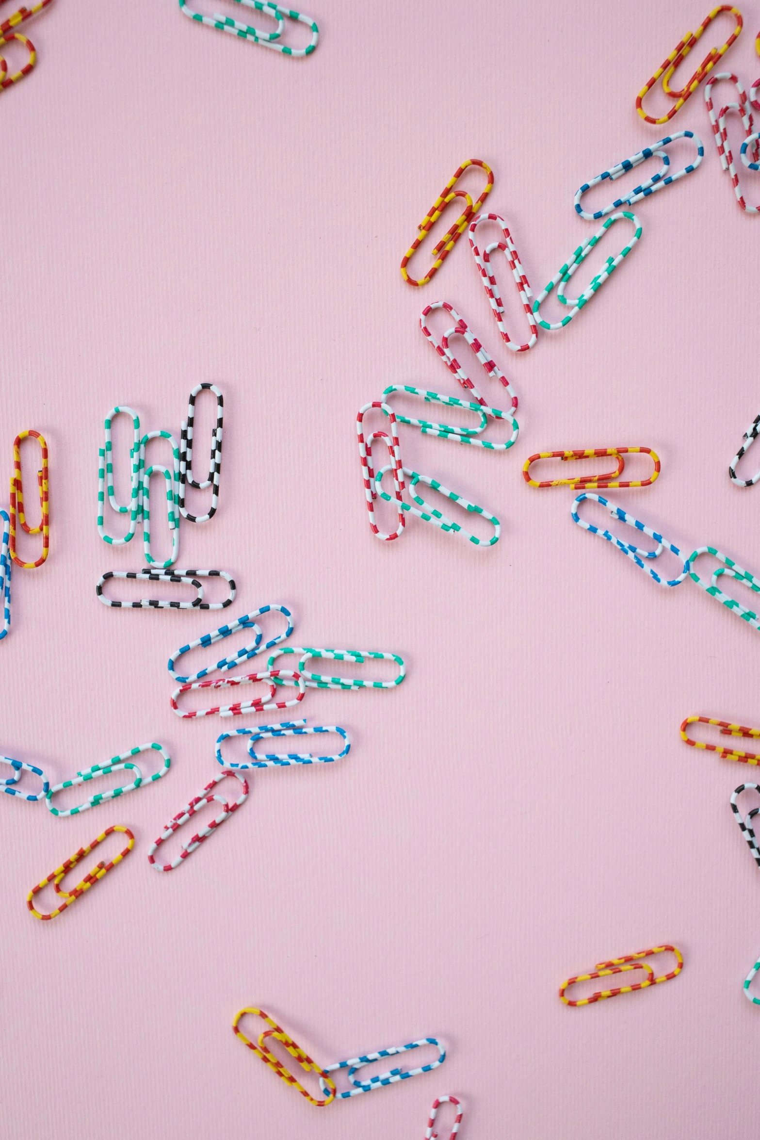 a bunch of paper clips laying on top of a pink surface, by Nicolette Macnamara, patterned, candy decorations, high quality product image”, multiple stories