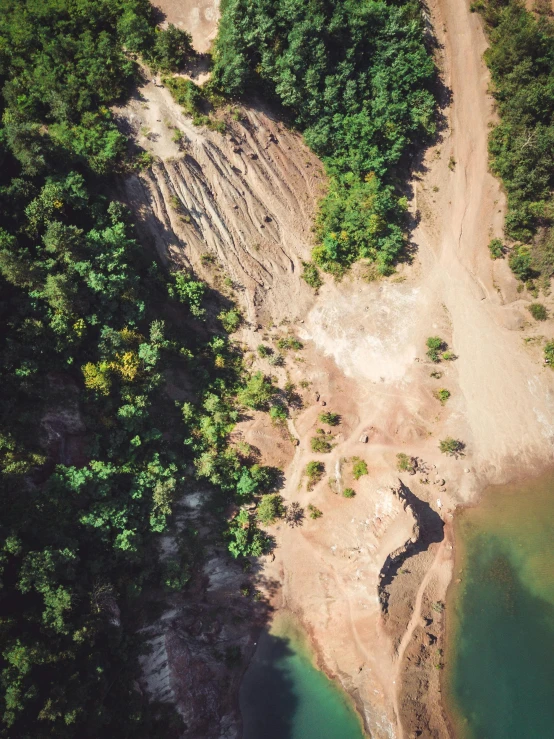 a large body of water next to a forest, by Adam Marczyński, unsplash, land art, landslide road, photo from the dig site, 2 5 6 x 2 5 6 pixels, sandstone