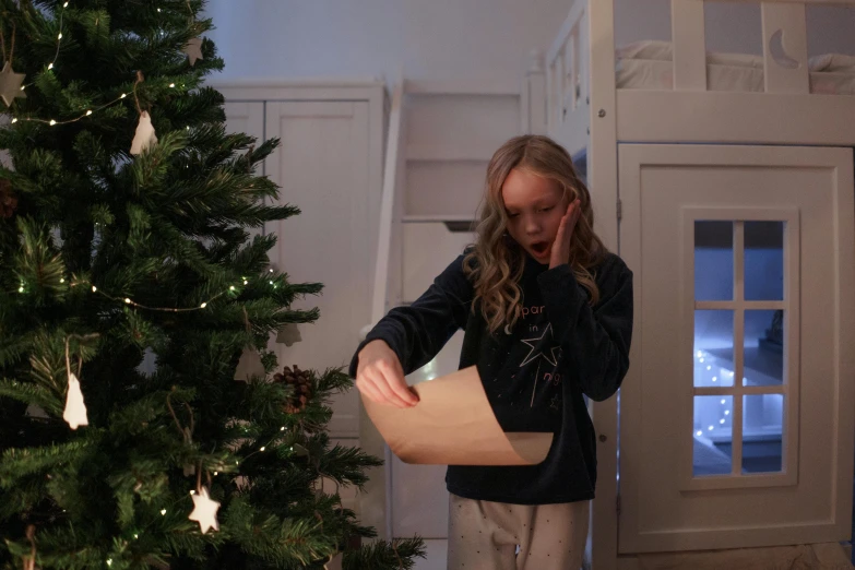 a little girl standing in front of a christmas tree, by Alice Mason, pexels contest winner, hyperrealism, reading a newspaper, in the bedroom at a sleepover, parchment paper, hidden message