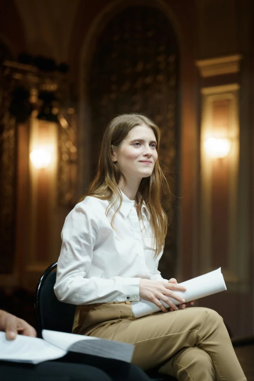 a woman in a white shirt sitting in a chair, inspired by Anna Füssli, trending on unsplash, hyperrealism, 3 actors on stage, still from a wes anderson film, portrait of alexandra daddario, audience