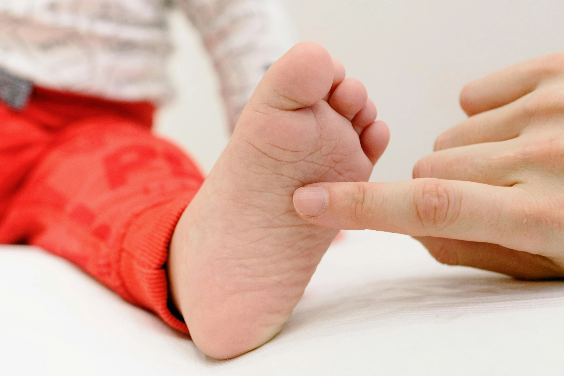 a close up of a person holding a baby's foot, with index finger, balance, very professional, scratchy