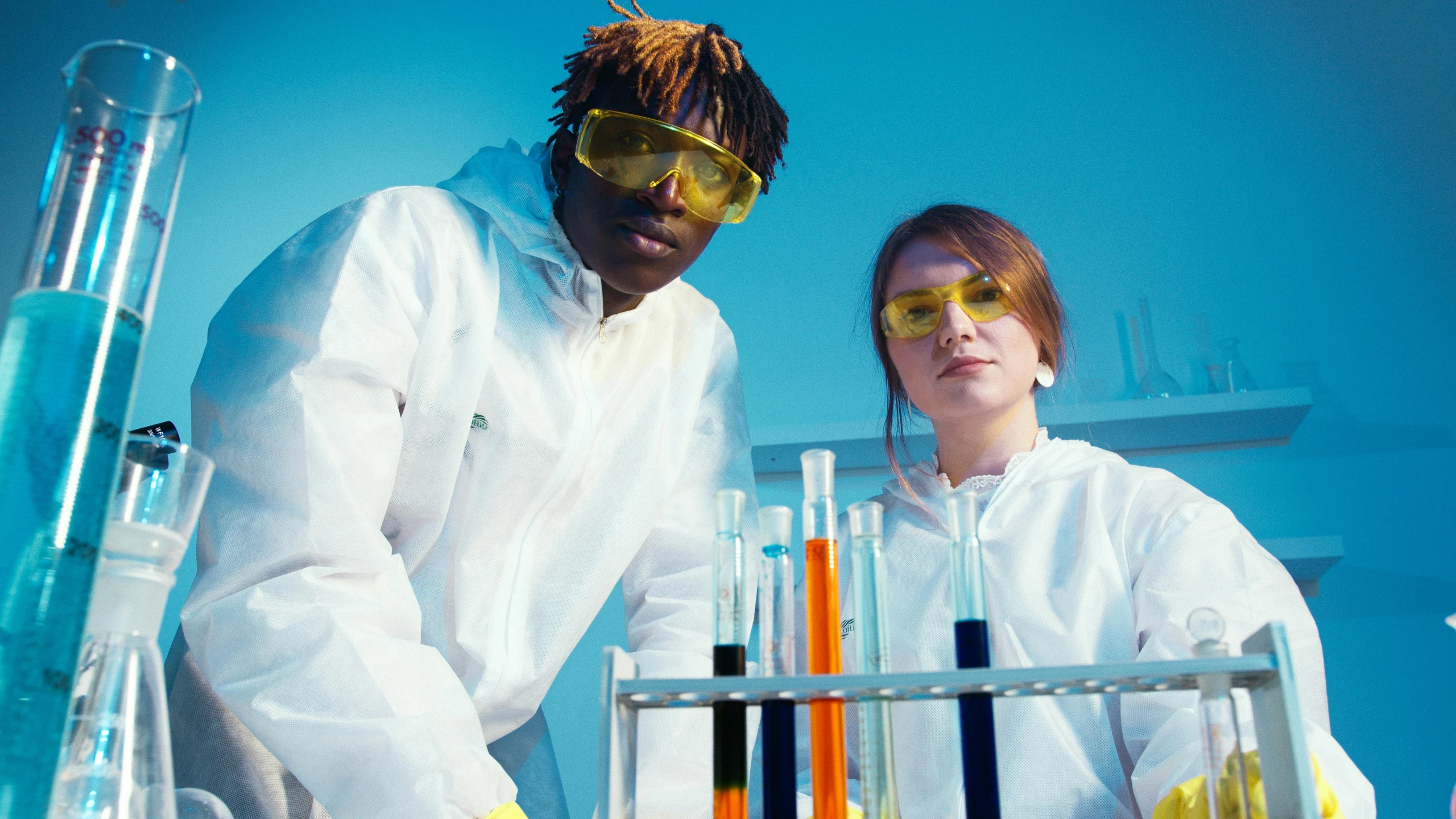 a couple of people standing next to each other in a lab, pexels, renaissance, fluorescent colours, mrbeast, labcoats, diverse