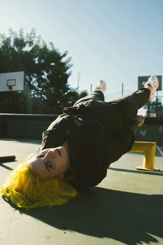 a man with yellow hair laying on a tennis court, inspired by Elsa Bleda, happening, kick flip, charli xcx, outside in parking lot, holding it out to the camera