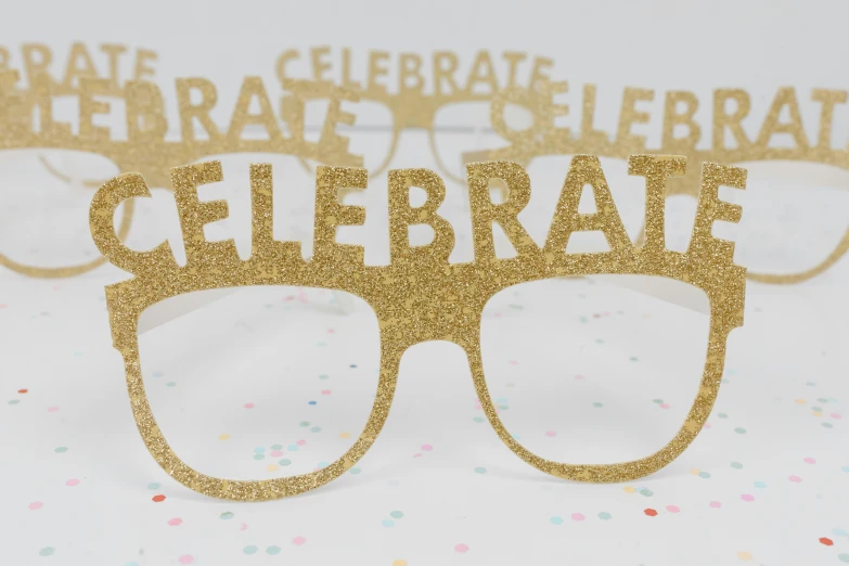 a pair of glasses sitting on top of a table, a picture, celebration costume, glowforge template, gold speckles, front closeup