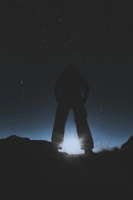 a person standing on top of a hill at night, at night