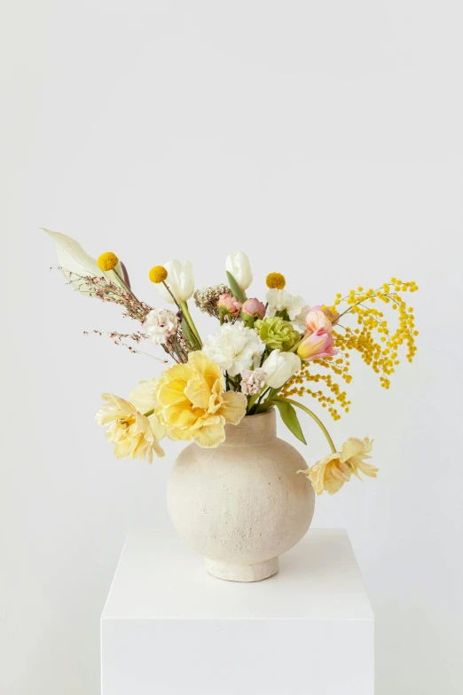 a white vase filled with yellow and white flowers, by Jessie Algie, unsplash, soft bright pastel, textured base ; product photos, centerpiece, made of glazed