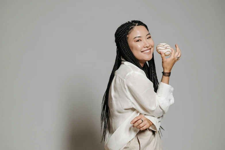 a woman holding a doughnut in one hand and a donut in the other, inspired by Kim Tschang Yeul, pexels contest winner, female baseball player, bjork smiling, an all white human, jamie chung