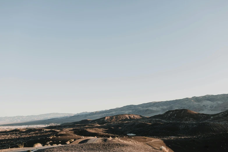 a man riding a motorcycle down a dirt road, by Lee Loughridge, unsplash contest winner, les nabis, overlooking martian landscape, hollister ranch, jagged metal landscape, muted colors with minimalism