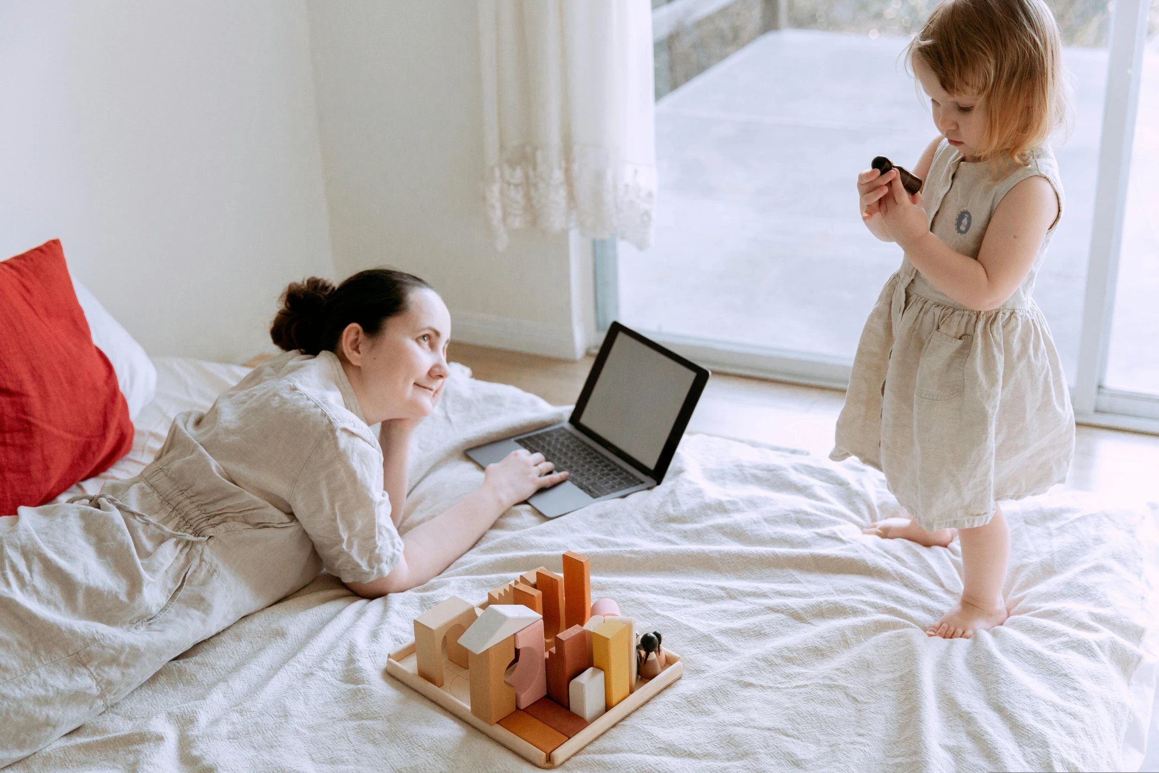 a woman and a child on a bed with a laptop, pexels contest winner, wooden art toys, full body image, inspect in inventory image, people at work