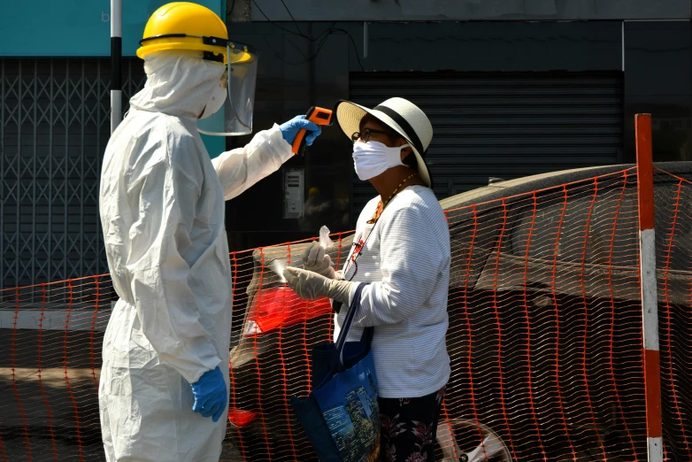 a couple of people that are standing in front of a fence, hazmat suits, erika ikuta, people at work, coronavirus