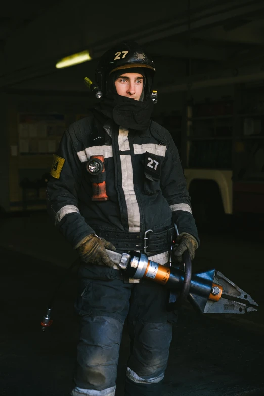 a man standing in a garage holding a chainsaw, a picture, by Adam Marczyński, pexels contest winner, young female firefighter, holding a rocket, gif, portrait of a male hydromancer