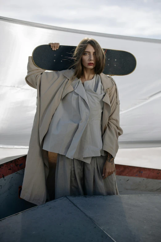 a woman holding a skateboard on top of her head, inspired by Peter Lindbergh, unsplash contest winner, renaissance, light brown trenchcoat, wearing long silver robes, wearing human air force jumpsuit, loose - fitting blouses