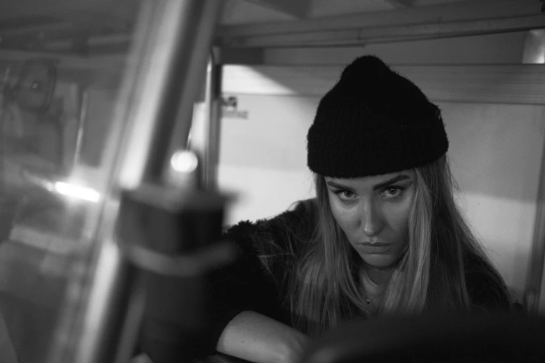 a black and white photo of a woman in a car, a black and white photo, unsplash, process art, wearing a beanie, florence pugh, girl in studio, sitting in a crane