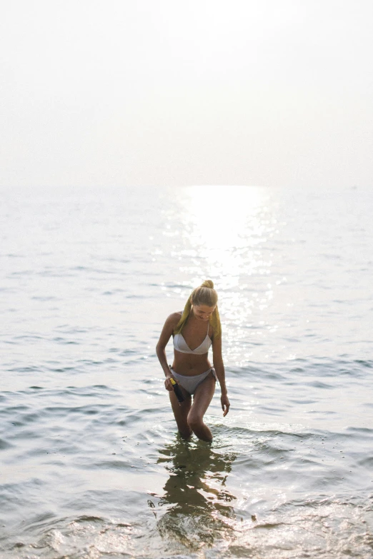 a woman in a bikini wading in the water, unsplash, minimalism, sunfaded, walking towards the camera, a blond, sea