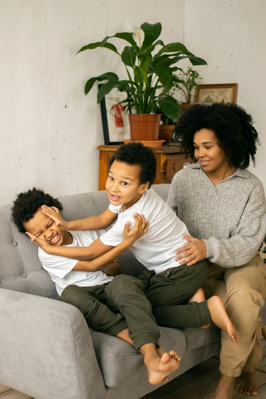 a woman and two children sitting on a couch, by Washington Allston, pexels contest winner, incoherents, playful pose, african american, cute boys, on a canva