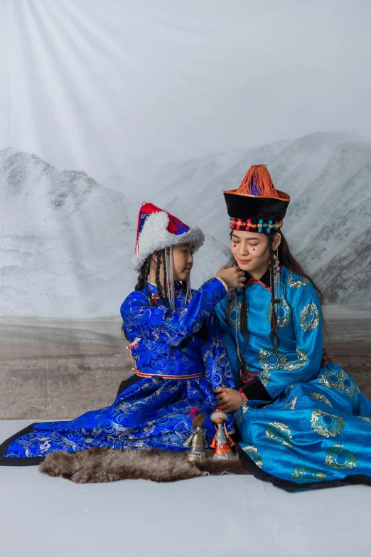a couple of people sitting on top of a snow covered ground, a portrait, inspired by Guo Xi, shutterstock contest winner, cloisonnism, costume with blue accents, ash thorp khyzyl saleem, young girls, ferred - themed robes and hat