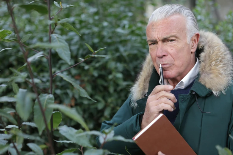 a man in a parka smoking a cigarette, inspired by Werner Andermatt, amongst foliage, holding notebook, white haired, profile image