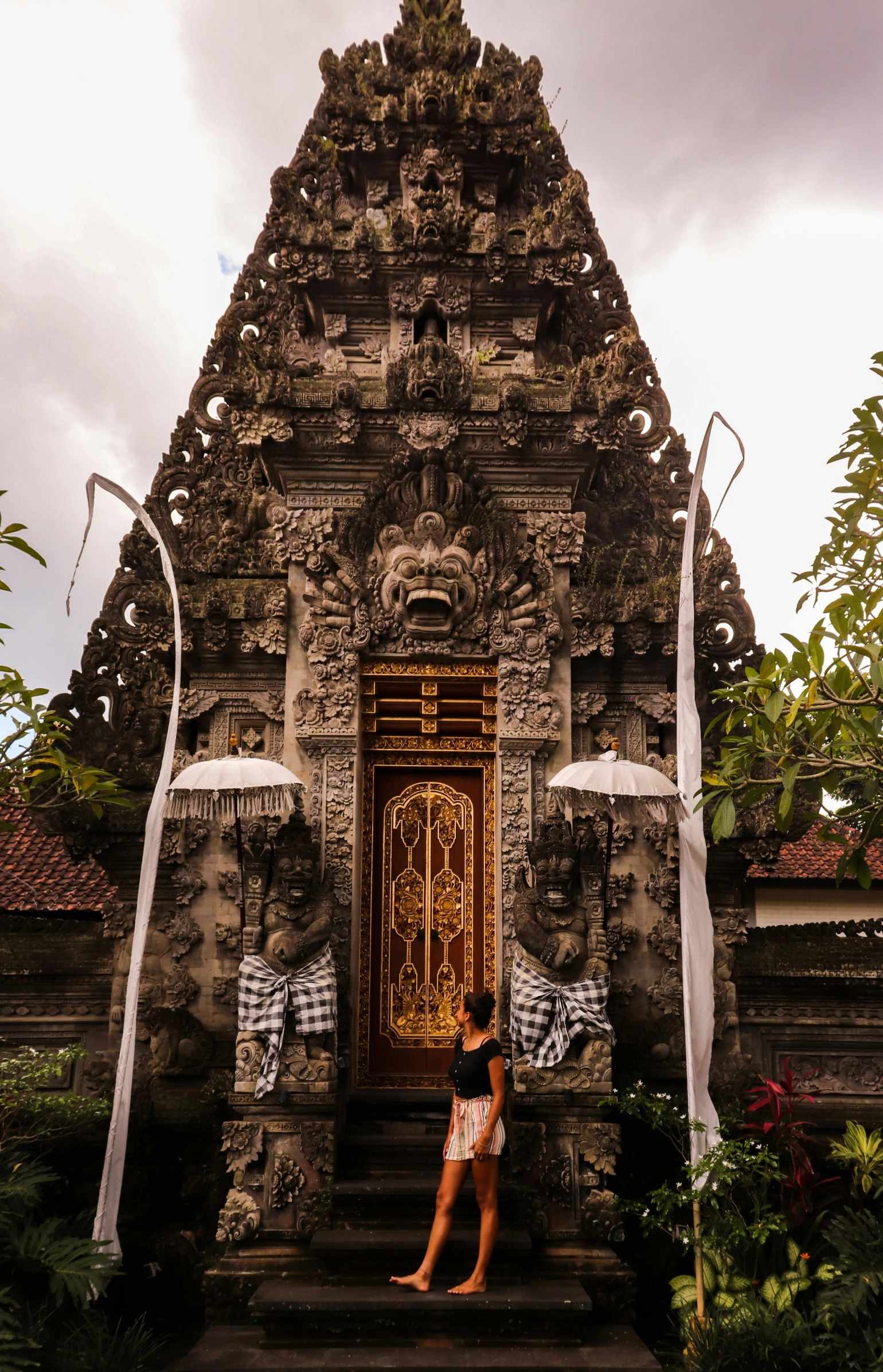 a woman standing in front of a stone building, inspired by I Ketut Soki, happening, intricate detailed roof, 8 k -