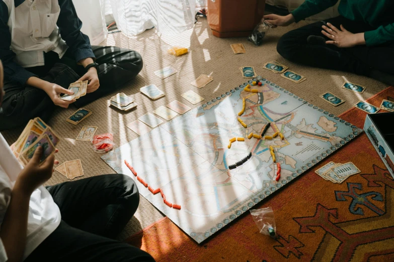 a group of people sitting on the floor playing a board game, by Carey Morris, unsplash contest winner, visual art, train far, 🦩🪐🐞👩🏻🦳, board games on a table, from east to west