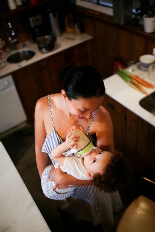 a woman feeding a baby in a kitchen, by Elizabeth Durack, pexels contest winner, renaissance, manuka, square, brown, ready to model