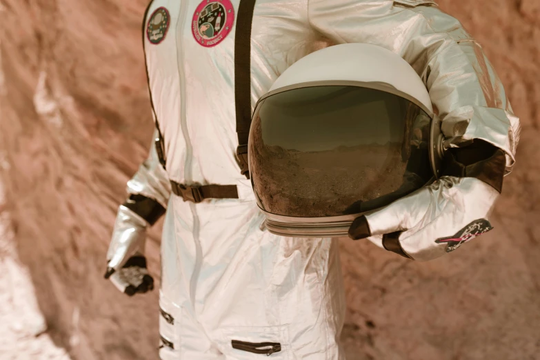 a man in a space suit holding a helmet, a colorized photo, pexels contest winner, wes anderson background, closed visor, lunar themed attire, top selection on unsplash