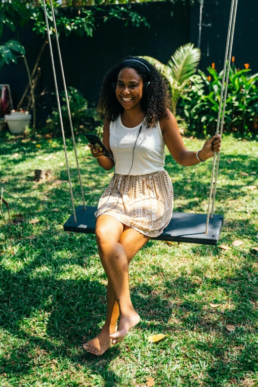 a woman sitting on a swing in a yard, with brown skin, jamaican vibe, having fun, exploration