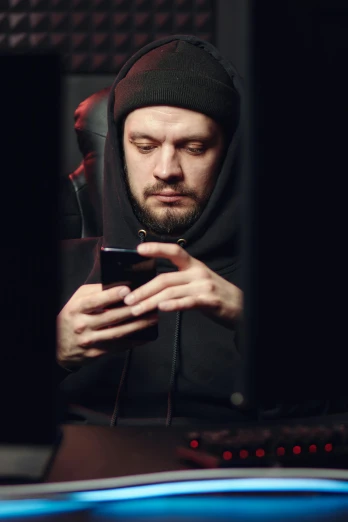 a man in a hoodie looking at his cell phone, a portrait, shutterstock, renaissance, twitch streamer, dark. no text, orthodox saint, taken in the late 2010s